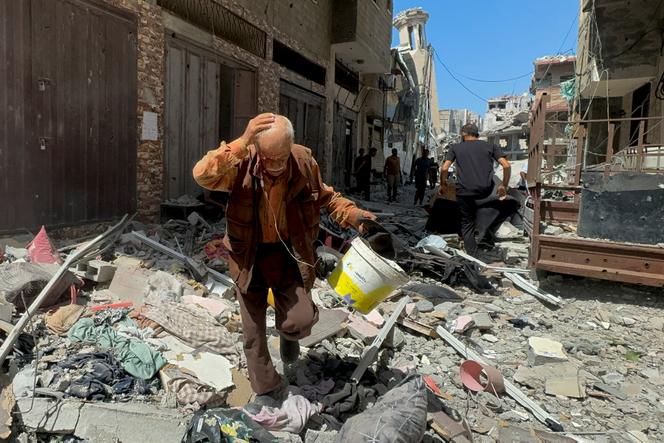 Un palestinese cammina vicino a un appartamento colpito durante un raid israeliano a Gaza City, il 26 agosto 2024. 