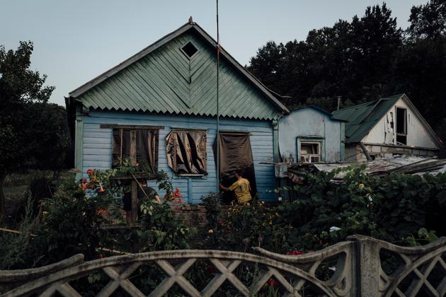 Neighbors cover windows blown out by a Russian bomb explosion in their neighbors' garden, in the village of Tokari, Sumy district, on August 25, 2024. One victim and one injured.
