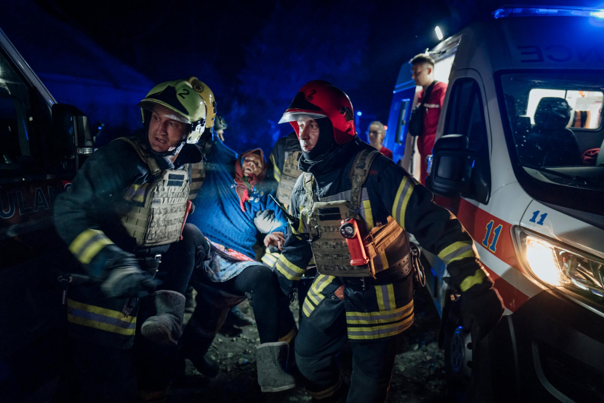 Ukrainian firefighters evacuate an elderly woman after a missile hit a residential area, Sumy, August 24, 2024.