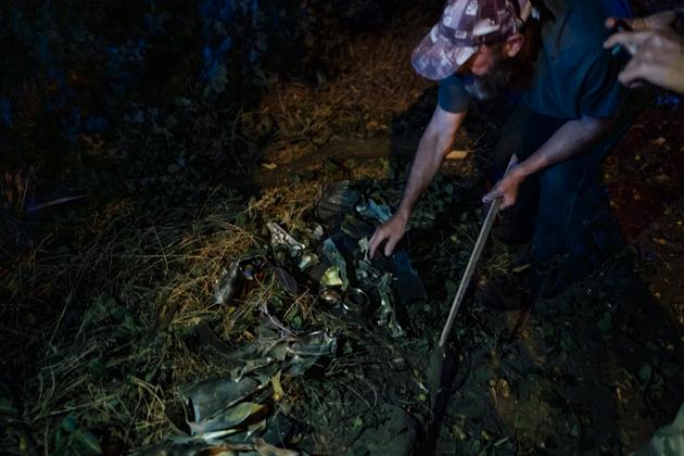 A Ukrainian civilian inspects the remains of a missile that has just fallen on a residential area in the town of Sumy, August 24, 2024.