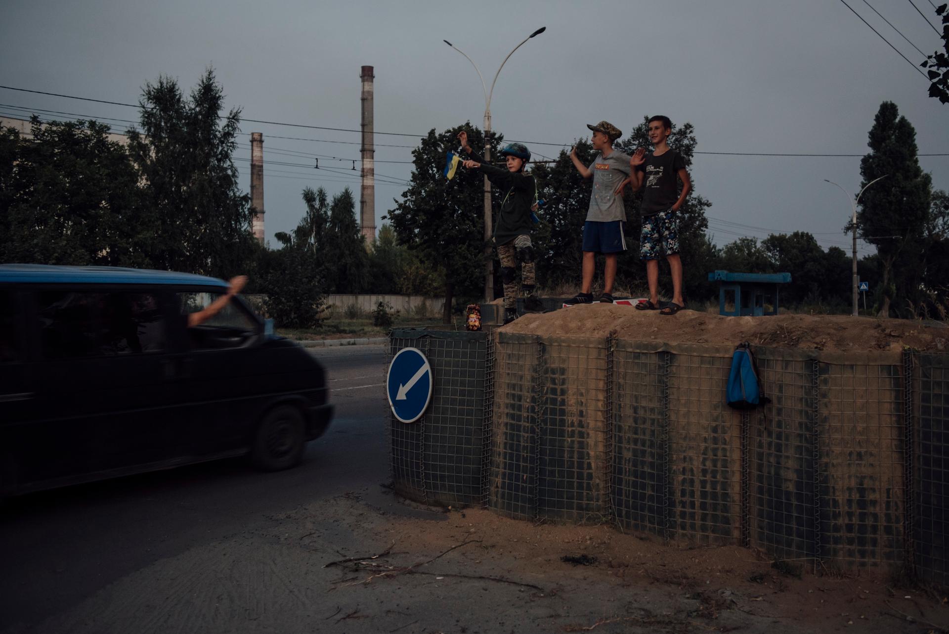 Children wave to cars at a checkpoint at the entrance to Sumy, August 21, 2024.