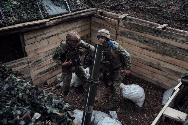 Two artillerymen from Ukraine's 117th Territorial Defense Brigade adjust their mortar after firing, in the Sumy region, August 23, 2024.
