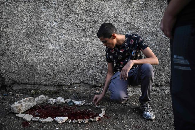 Un jeune Palestinien observe des taches de sang entourées de pierres dans la petite ville de Zababdeh, au sud-est de Jénine, en Cisjordanie, le 30 août 2024, à la suite d’un raid de l’armée israélienne.