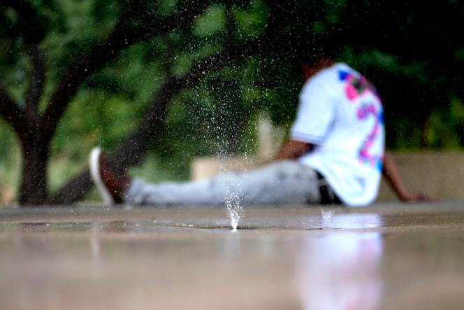 Un homme tente de se rafraîchir dans une aire de jeux pour enfants à Phoenix, en Arizona, le 25 juin 2024.