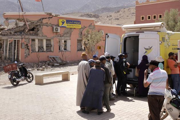People stand near a van used as a mobile bank in Douar Talat N'Yaaqoub, in Morocco's el-Haouz province in the High Atlas Mountains south of Marrakesh, on September 5, 2024.