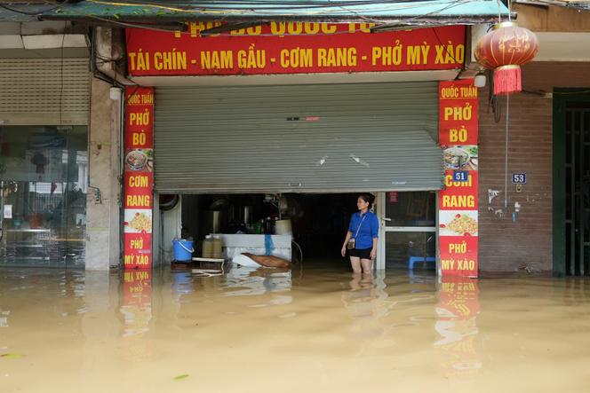 Une femme se tient devant son restaurant après le passage du typhon Yagi, à Hanoï, au Vietnam, le 12 septembre 2024.