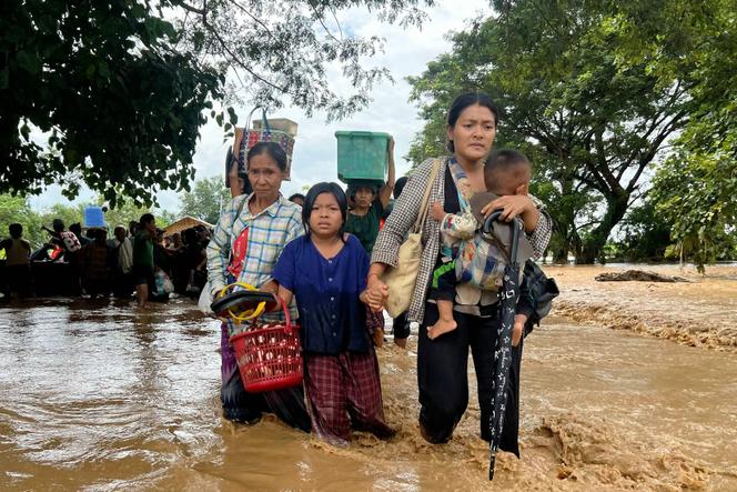 Des habitants marchent dans les eaux de crue à Pyinmana, dans la région birmane de Naypyidaw, le 13 septembre 2024, après les fortes pluies du typhon Yagi.