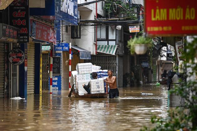 People carry staples on a boat through floodwaters on a street in Hanoi (Vietnam), September 12, 2024.