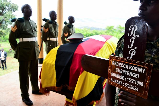 Des soldats des Forces de défense du peuple ougandais (UPDF) se tiennent près du cercueil recouvert du drapeau de l'olympienne ougandaise assassinée Rebecca Cheptegei, avant son enterrement dans le district de Bukwo, en Ouganda, le 14 septembre 2024.
