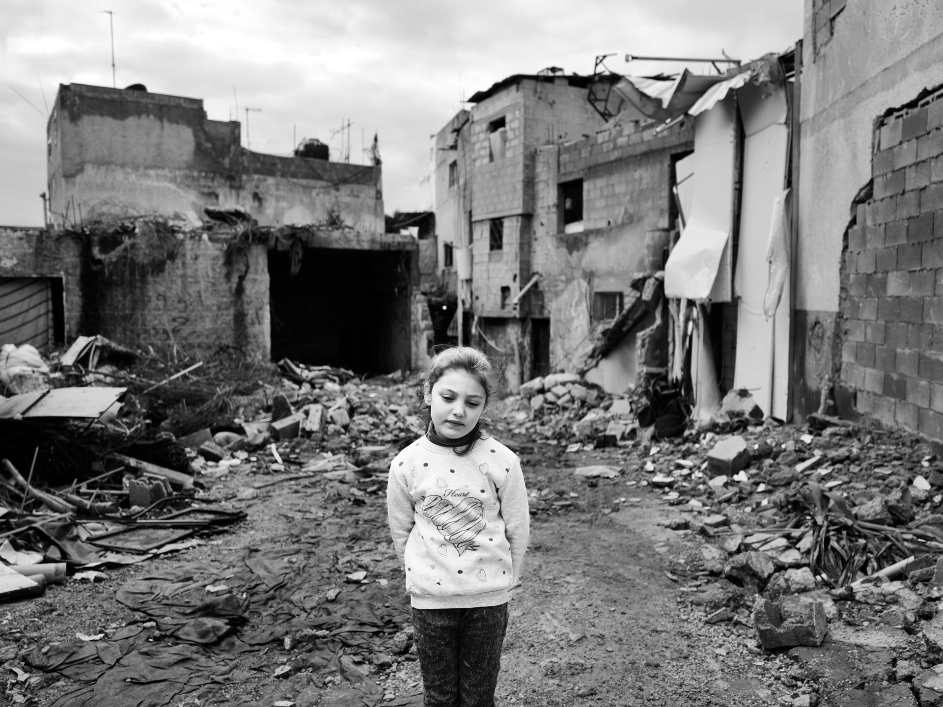 <b>Israa Ar'arawi, in front of her home in the Jenin camp (West Bank), February 2024. </b><br>
<br>
Khader remembers when he asks her, <i>"Hi Israa, what's your dream?"</i> Silence. She looks up, takes a deep breath, then looks down. <i>"I want to die,"</i> she whispers. <i>"What?" "I want to die. "But Israa, if I die and you die, who will rebuild our land?"</i> She looks down again, her voice soft as she begins to speak. <i>"I'm so tired of the explosions, the destruction. I'm tired of the Israelis, always destroying everything. They come into our house and point their guns at us. I'm so scared. I just want everything to end. I'm so tired. So, so tired."</i>