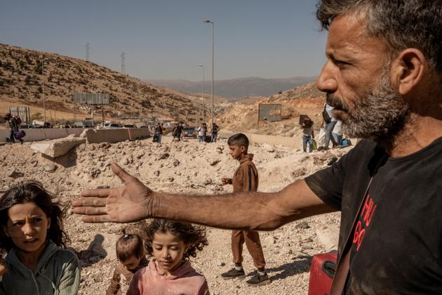 Ali (right) and his family of 11 children, who originally hailed from Syria, at the Masnaa border crossing between Lebanon and Syria, October 6, 2024. They had left Ouzai, in the southern suburbs of Beirut, in the early hours of the morning, after a night of bombing; and sought to move in with relatives on the outskirts of Damascus.