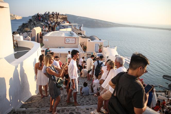 Turistas aguardam o pôr do sol na vila de Oia, na ilha grega de Santorini, em 20 de julho de 2024.