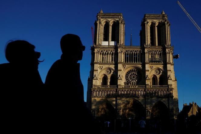 No dia 23 de outubro de 2024, transeuntes passam em frente à Catedral de Notre-Dame de Paris, devastada por um incêndio em 2019, enquanto prosseguem os trabalhos de restauro antes da sua reabertura em dezembro, em Paris.