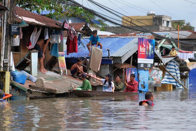 Des personnes à bord d’un bateau mènent des opérations de secours dans une zone inondée en raison des fortes pluies provoquées par la tempête tropicale Trami à Naga, dans la province de Camarines, aux Philippines, le 25 octobre 2024. 