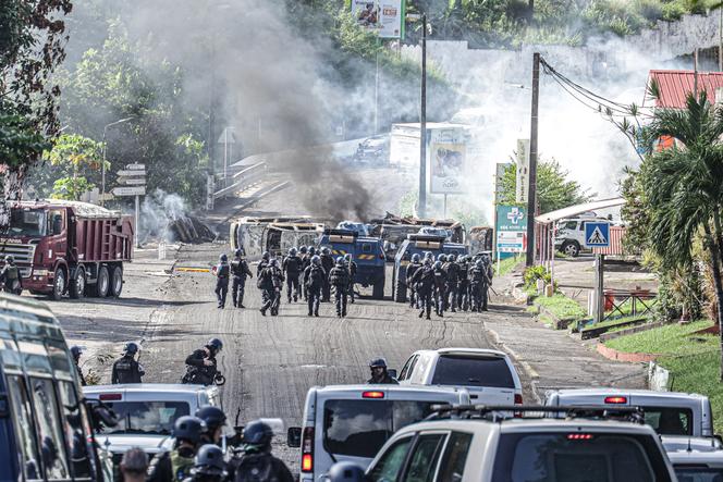 Des gendarmes avancent en direction d’un barrage érigé par des militants contre la vie chère, sur la RN2, à Case-Pilote (Martinique), le 24 octobre 2024. Il s’agit de l’axe qui permet de relier Fort-de-France à la ville de Saint-Pierre.