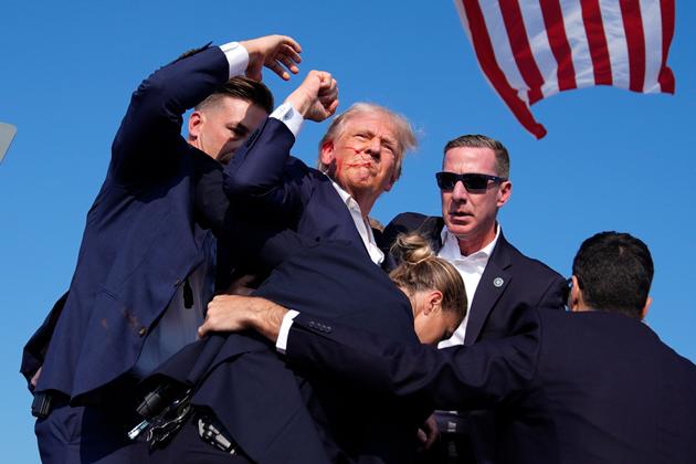 Donald Trump, wounded after a shooting, is surrounded by US Secret Service agents at an election rally, July 13, 2024, in Butler, Pennsylvania.