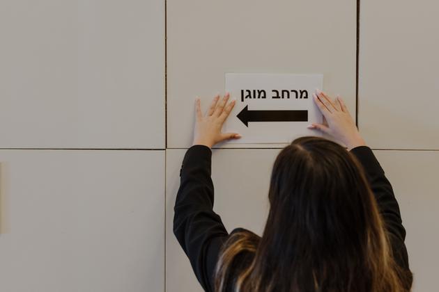 The hotel employee hangs a sign in the lobby with an arrow pointing to the "refuge," to take cover during attacks. October 28, 2024