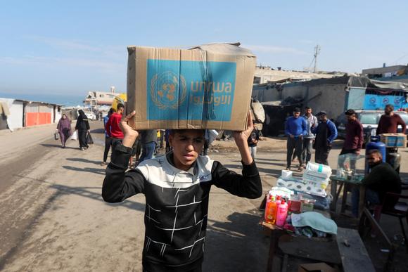 Un jeune palestinien transporte un carton d’aide distribué par l’UNRWA, à Deir Al-Balah, dans le centre de la bande de Gaza, le 4 novembre 2024.