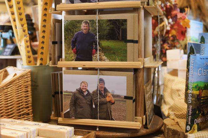 Des portraits des personnages de l’émission sur des cartes postales vendues dans la boutique de la ferme de Jeremy Clarkson, à Chadlington (Angleterre), le 24 octobre 2024. Gerald Cooper (en haut), le responsable sécurité, et Jeremy Clarkson (avec le porcelet), au côté de Kaleb Cooper, ouvrier agricole.