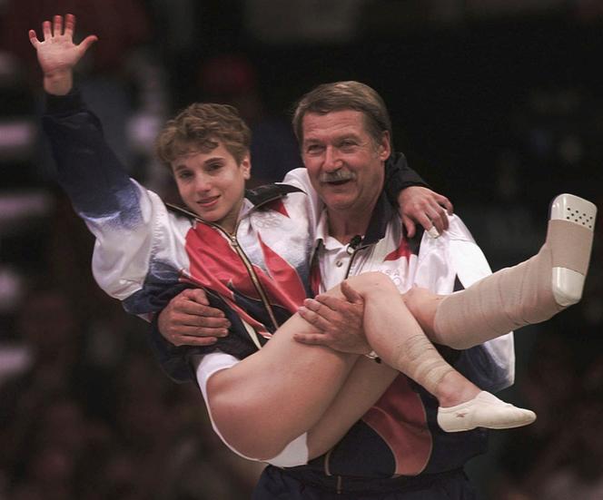 Bela Karolyi carrega a ginasta Kerri Strug, medalhista de ouro, lesionada no tornozelo, durante a competição por equipes femininas nos Jogos Olímpicos de Verão de Atlanta, Estados Unidos, em 23 de julho de 1996.