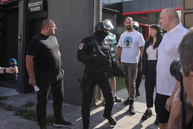 Andrew Tate (au centre) est escorté par la police roumaine à la sortie de son domicile, lors d’une perquisition le 21 août 2024.
