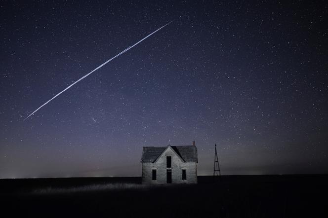 Sur cette photo prise avec une longue exposition, une chaîne de satellites SpaceX StarLink d’Elon Musk passe au-dessus d’une vieille maison en pierre près de Florence, au Kenya, le 6 mai 2021.