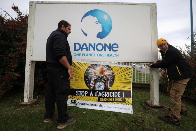 Des membres du syndicat agricole Coordination rurale accrochent une banderole « Stop agricide » sur le panneau d’entrée du site de Danone dans le cadre de son blocage, à Villecomtal-sur-Arros, dans le sud-ouest de la France, le 26 novembre 2024.