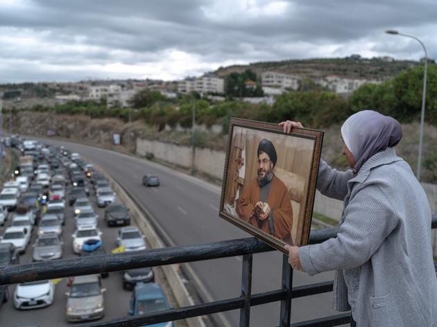 A woman with a portrait of Hassan Nasrallah, overlooking traffic jams on the road leading to southern Lebanon, November 27, 2024.