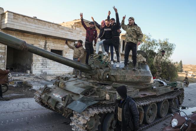 Des combattants rebelles posent au sommet d'un char de l'armée syrienne capturé dans la ville de Maarat Al-Numan, au sud-ouest d'Alep, en Syrie, le samedi 30 novembre 2024.