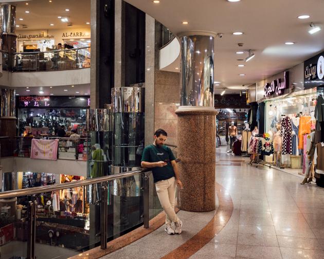 Un vendeur fume une cigarette en attendant les clients dans le centre commercial Hebron Center, en Cisjordanie, le 16 octobre 2024.