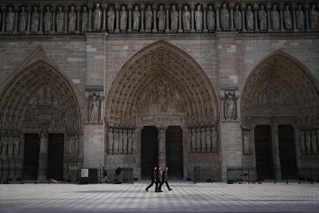 Rescue workers walk past the main entrance of Notre-Dame on Saturday morning.