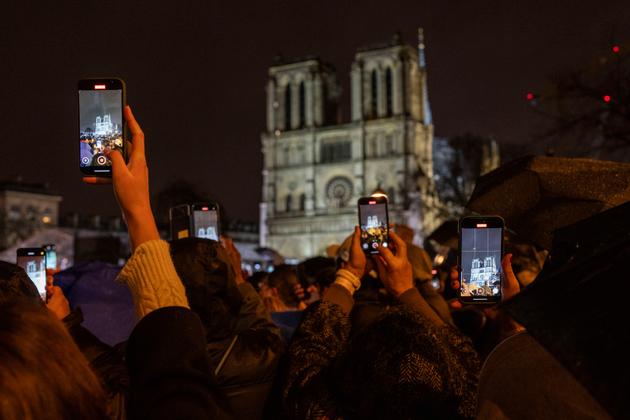 Spectators take snapshots outside Notre-Dame.