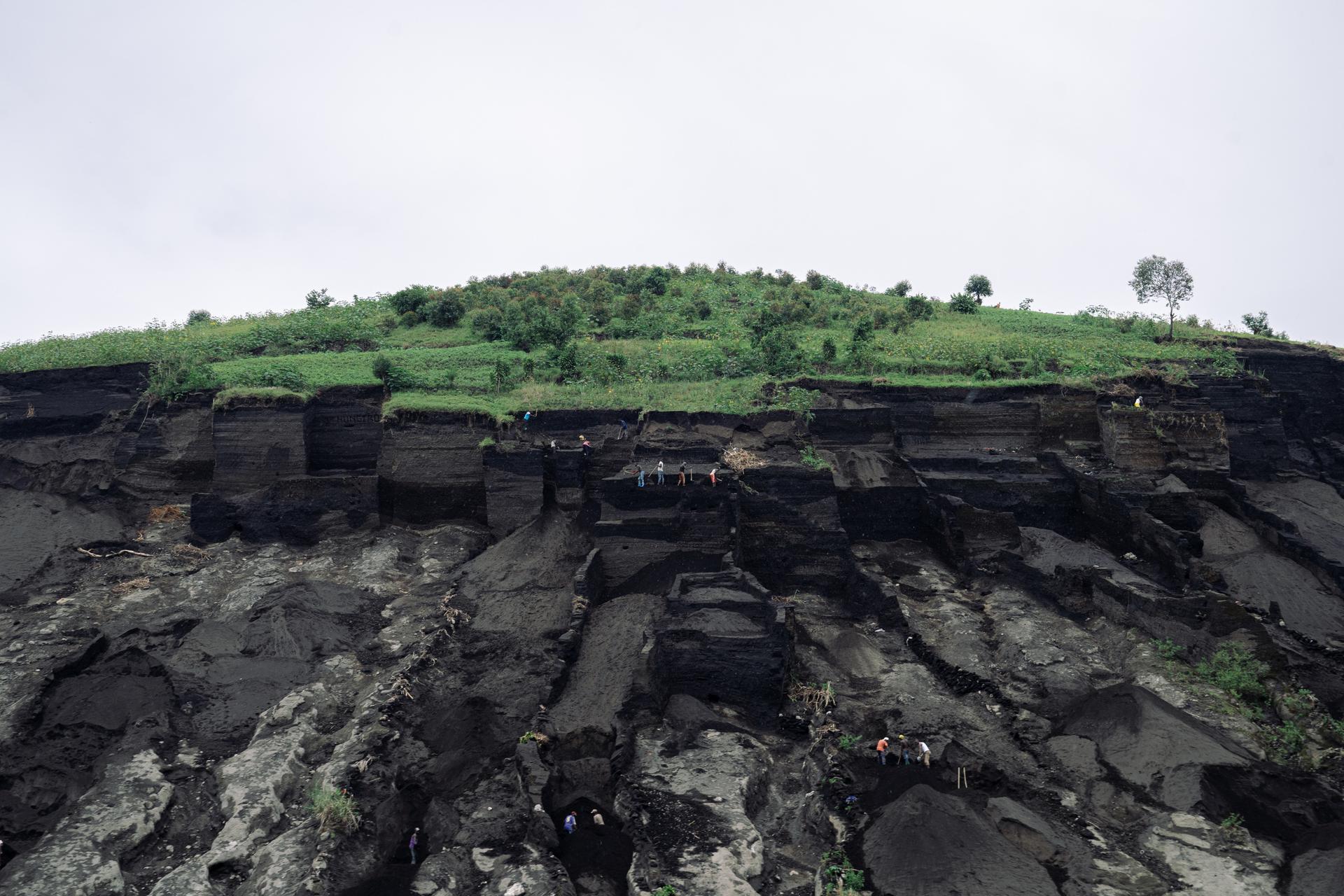 Os escavadores extraem terra das colinas acima do campo de deslocados de Bulengo para usar como material de construção.