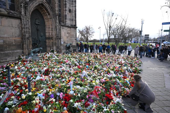 Pessoas se reúnem em frente a flores e velas deixadas em homenagem às vítimas perto do mercado de Natal, dois dias após o ataque mortal, em Magdeburg, Alemanha, em 22 de dezembro de 2024.  