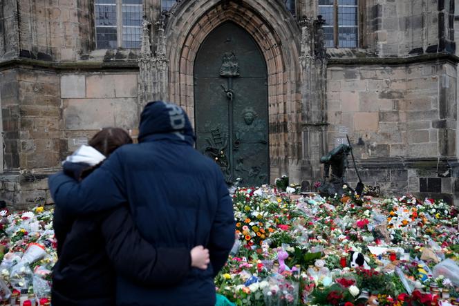 Um casal se abraça diante de flores e velas deixadas em frente à Igreja Johannis, perto do mercado de Natal, onde um carro atropelou a multidão na noite de sexta-feira, em Magdeburg, Alemanha, 22 de dezembro de 2024.