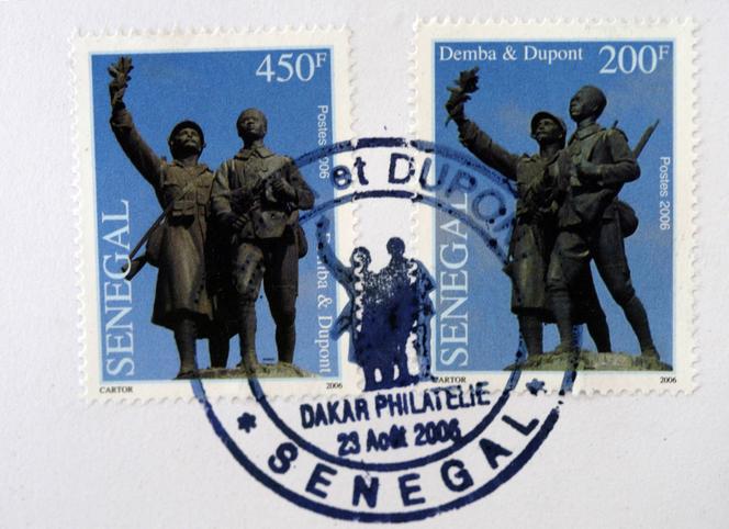 Selos senegaleses representando a estátua “Demba & Dupont” erguida no bairro Plateau de Dakar.