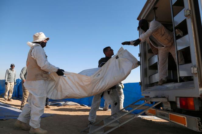 Especialistas forenses carregam restos humanos exumados de uma vala comum em um veículo em Tal al-Shaikhia, província de Muthanna, sul do Iraque, em 25 de dezembro de 2024.