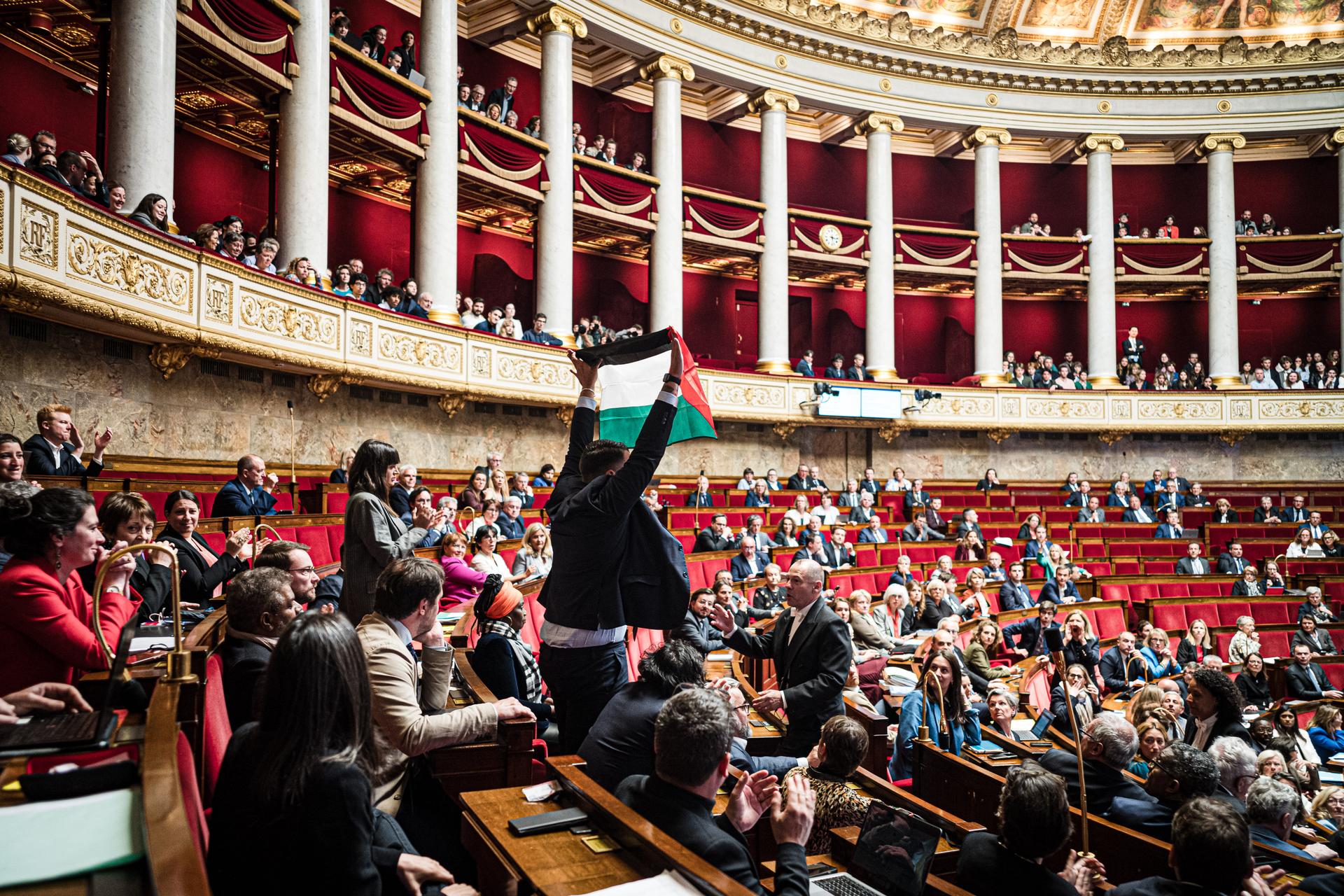 During a questions to the government session, radical left La France Insoumise party MP Sébastien Delogu waves a Palestinian flag, in Paris, on May 28, 2024. He was sanctioned with a 50% reduction in his parliamentary allowance for two months, and a fortnight's suspension from the Assemblée.