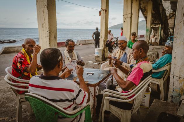 Homens jogam cartas ao longo da costa em Mutsamudu, Comores, em 27 de dezembro de 2024. 