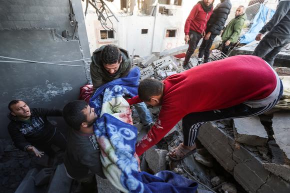 Des Palestiniens portent le corps d’un enfant, sur le site d’une frappe israélienne sur une maison, à Nousseirat, dans le centre de la bande de Gaza, le 9 janvier 2025.