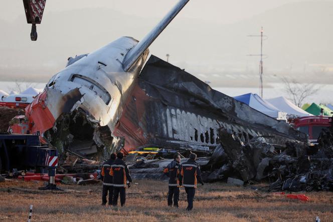 Des pompiers examinent l’épave de l’avion qui s’est écrasé après être sorti de piste, à l’aéroport international de Muan,  en Corée du Sud, le 31 décembre 2024.