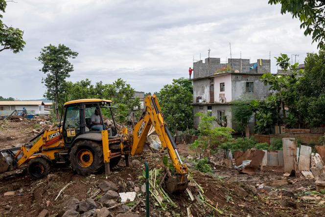 Des ouvriers de la ville de Mamoudzou évacuent les débris des bangas rasés par l’ouragan à côté d’une maison construite «&nbsp;en dur&nbsp;», à Kaweni, Mayotte, le 17&nbsp;décembre 2024. 