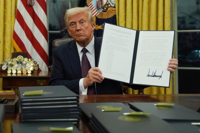 Donald Trump brandit un des premiers décrets qu’il a signés dans le bureau Ovale de la Maison Blanche, à Washington  le 20 janvier 2025.