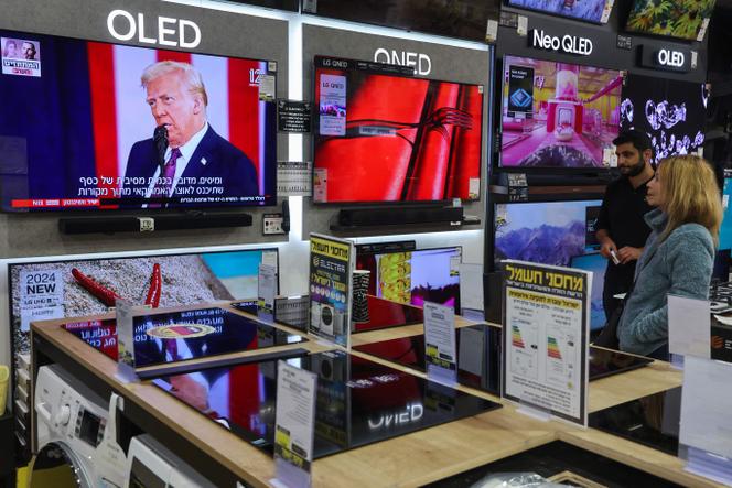 Pessoas assistem ao discurso de posse de Donald Trump em 20 de janeiro de 2025, na vitrine de uma loja em Modiin, Israel.
