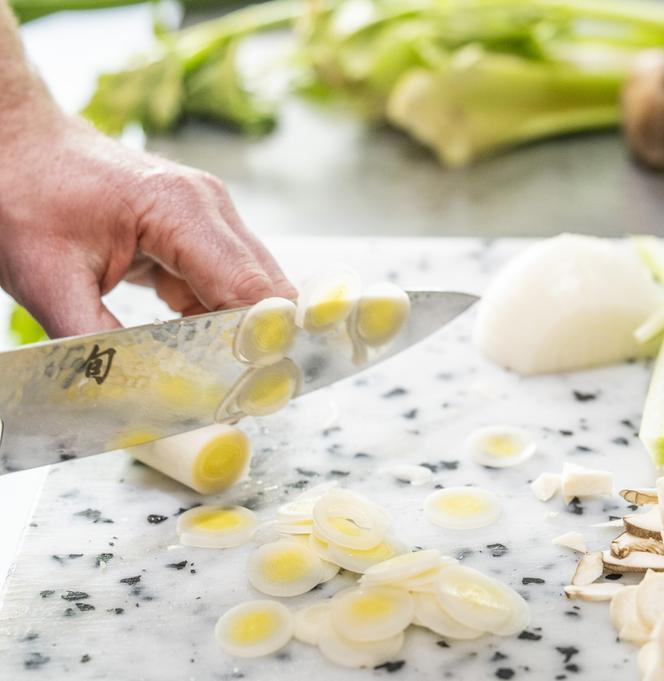 Le chef Maxime Schelstraete teste l’efficacité d’un couteau pour émincer finement un blanc de poireau fibreux.