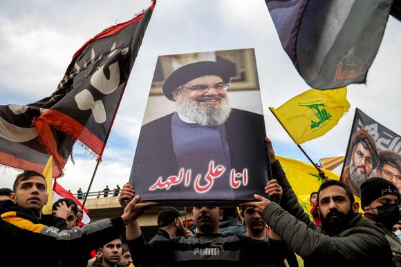 Des manifestants tiennent une pancarte représentant Hassan Nasrallah, le leader assassiné du mouvement islamiste chiite libanais Hezbollah, lors d’un rassemblement organisé par le Hezbollah pour bloquer la route de l’aéroport international de Beyrouth suite à une décision d’interdire à deux vols iraniens d’y atterrir, à Beyrouth, le 15 février 2025.