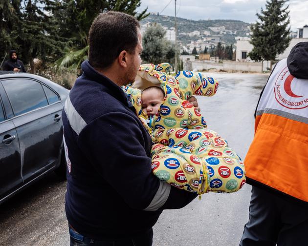 Un membre du Croissant-Rouge palestinien tient dans ses bras Adam, 6 mois, dans le village d’Anabta (Cisjordanie), où le nourrisson et sa mère Yasmine ont trouvé refuge après avoir quitté le camp de Nour Shams, le 10 février 2025.