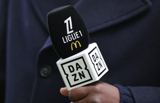 Un speaker tient un micro avec le logo du diffuseur TV DAZN avant le match de Ligue 1 entre le FC Nantes et le RC Lens, au Stade de la Beaujoire, le 23&nbsp;février 2025.