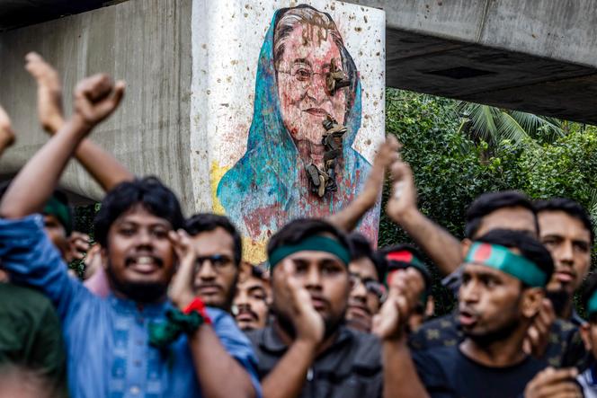 Près d’une peinture murale vandalisée de l’ex-première ministre du Bangladesh, Sheikh Hasina, évincée en août 2024, lors d’un rassemblement d’étudiants réclamant des comptes et un procès contre elle, près de l’université de Dacca, le 12 août 2024.