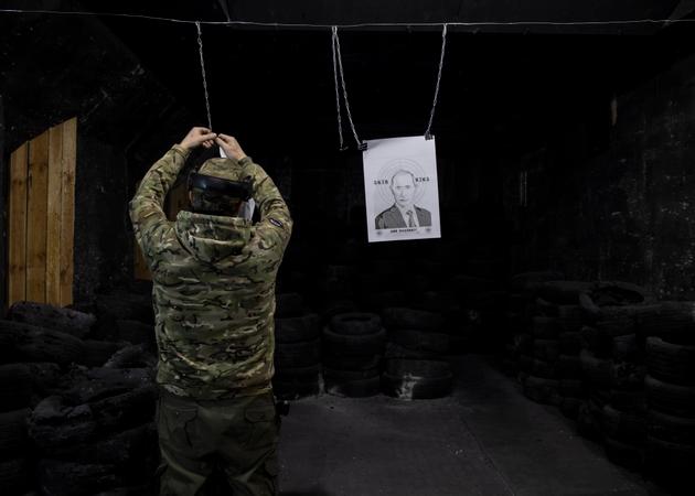 An employee hangs targets printed with the face of Russian president Vladimir Putin, at a shooting range in Kyiv, February 17, 2025.